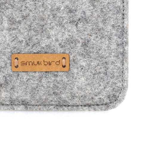Detail einer grauen Samsung Galaxy A37-Hülle aus Filz mit Lederanhänger „smukbird“, die hochwertige Handwerkskunst zeigt.