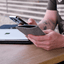Stylishe Handytasche in hellgrau für Google Pixel 10 Pro Fold aus Wollfilz, gehalten von einer Person, mit Laptop im Hintergrund.