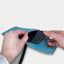 Person, die ein Motorola Edge 60 fusion in eine stilvolle hellgraue und blaue Filztasche mit Schulterriemen steckt.